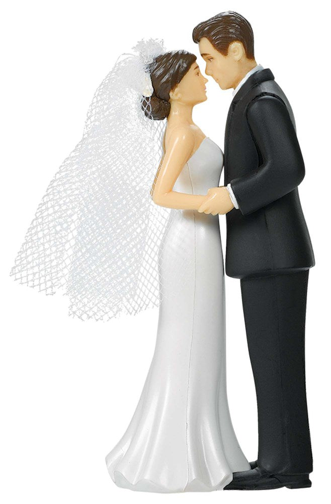 Bride and groom cake topper with bride in white gown and veil, groom in black tuxedo, embracing pose.