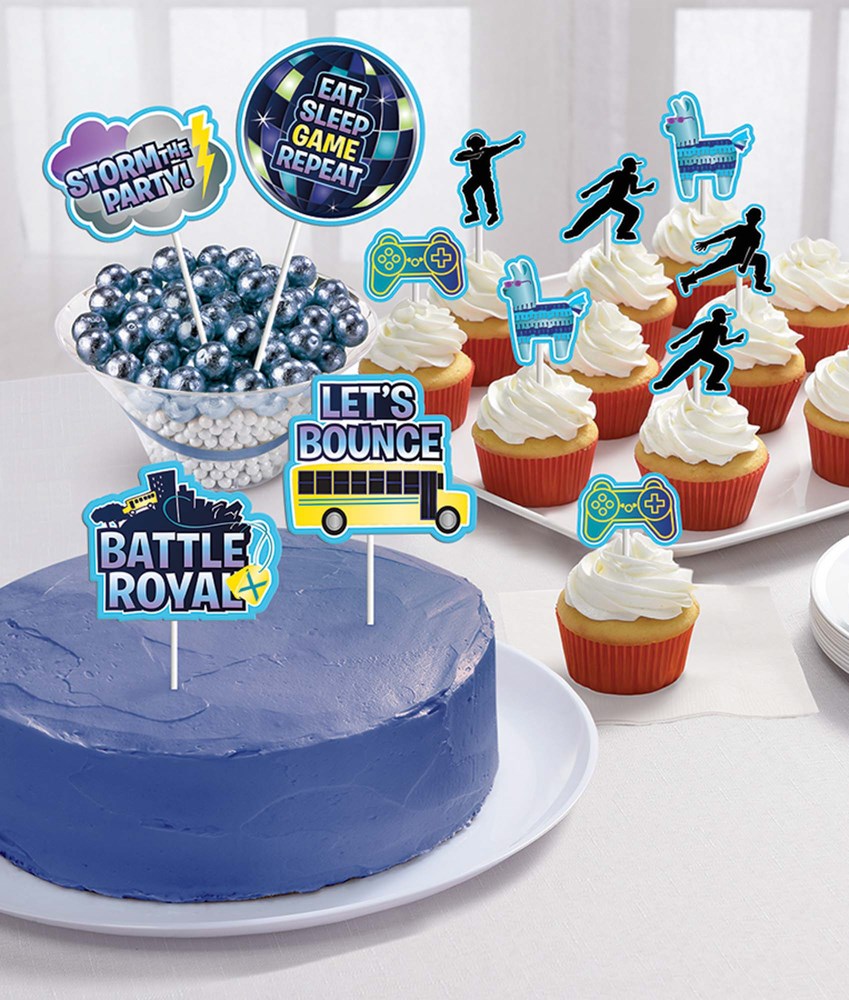 Blue frosted round cake with silver pearl toppers and colorful Battle Royal themed paper toppers, cupcakes with white.