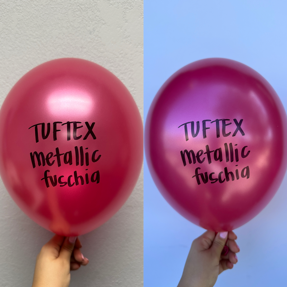 Two shiny metallic fuchsia 11-inch latex balloons with "Tuftex metallic fuschia" printed in black, held by hand against.