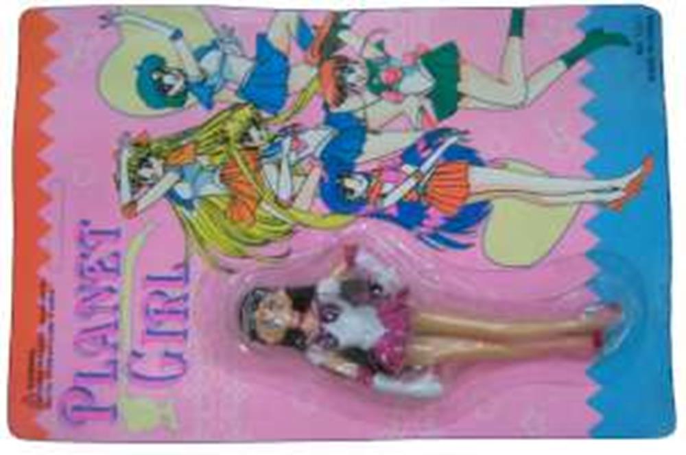 Small female doll with long brown hair, pink outfit, and accessories on colorful pink and blue packaging with cartoon.