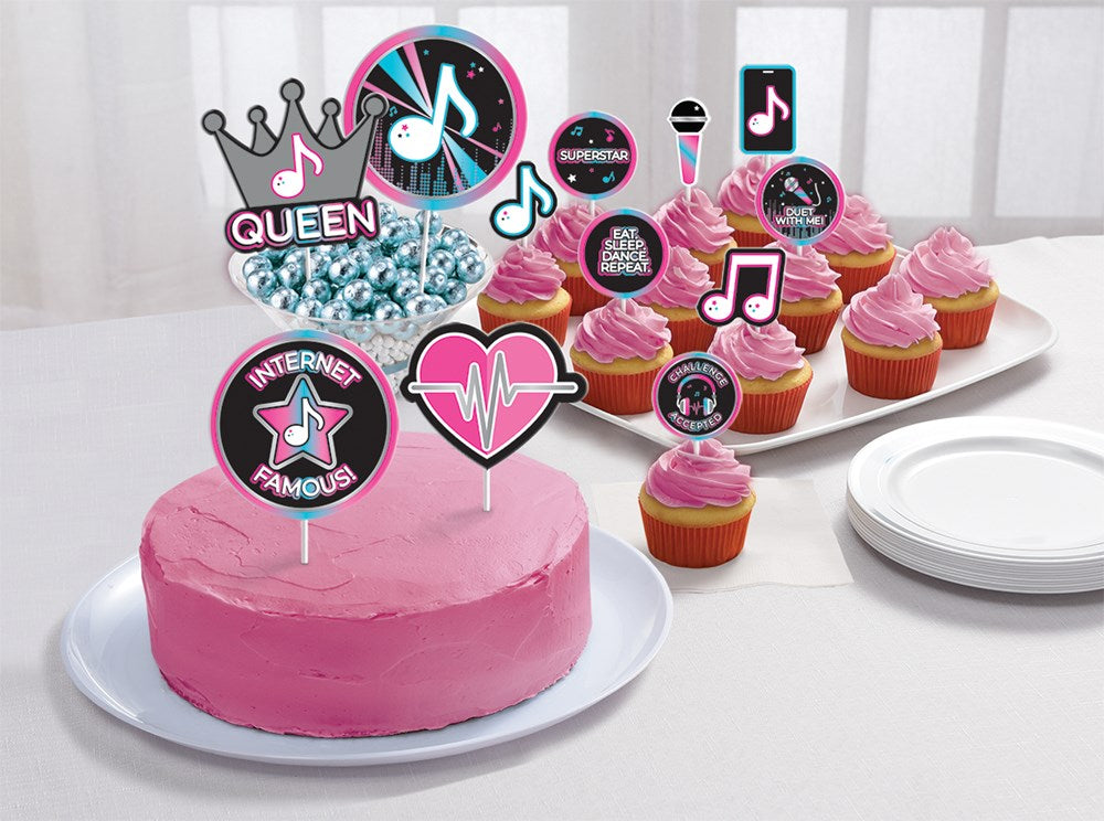 Pink frosted cake and cupcakes decorated with birthday topper kit featuring internet-themed icons in black, pink, blue, and.