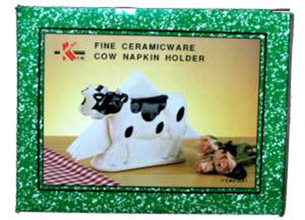White ceramic cow-shaped napkin holder with black spots and a rectangular slot for napkins.