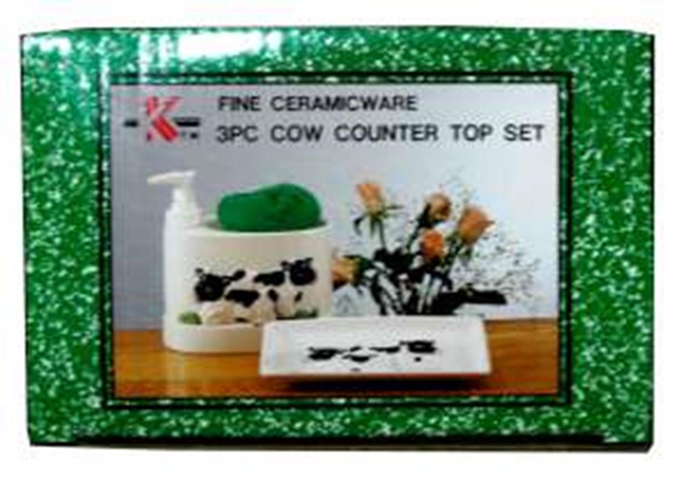 Ceramic cow-themed countertop set with three pieces in white and black spots on green speckled box.