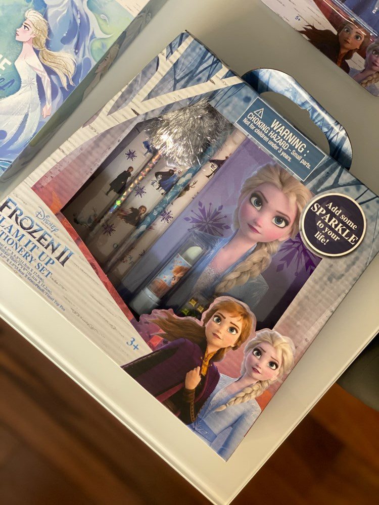 Frozen 2 stationery set featuring characters Elsa, Anna, and Olaf on blue and purple paper with snowflake designs, packaged.
