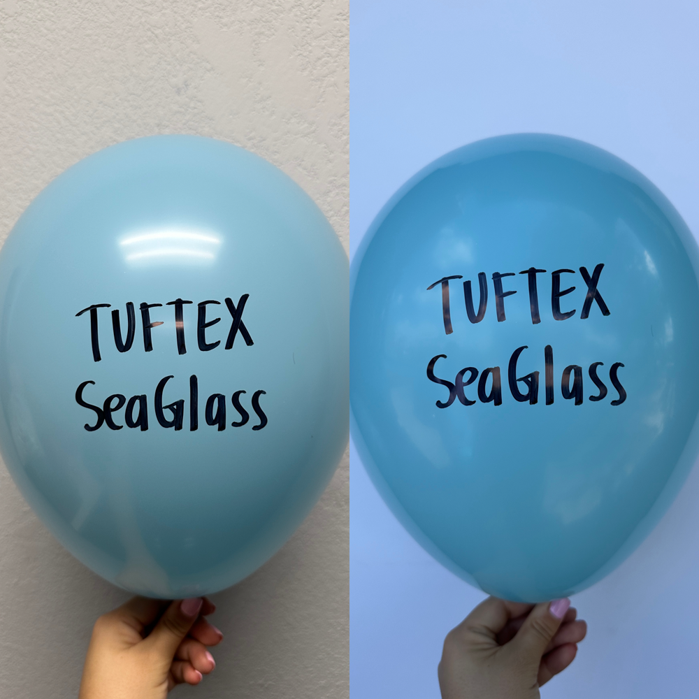 Two 17-inch sea glass blue latex balloons with "Tuftex SeaGlass" printed in black font, held against light and blue.