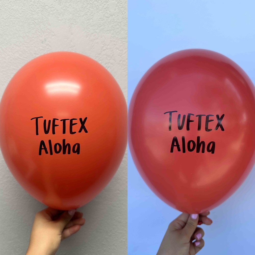 Two shiny red 17-inch latex balloons with "Tuftex Aloha" printed in black text, held by hand.