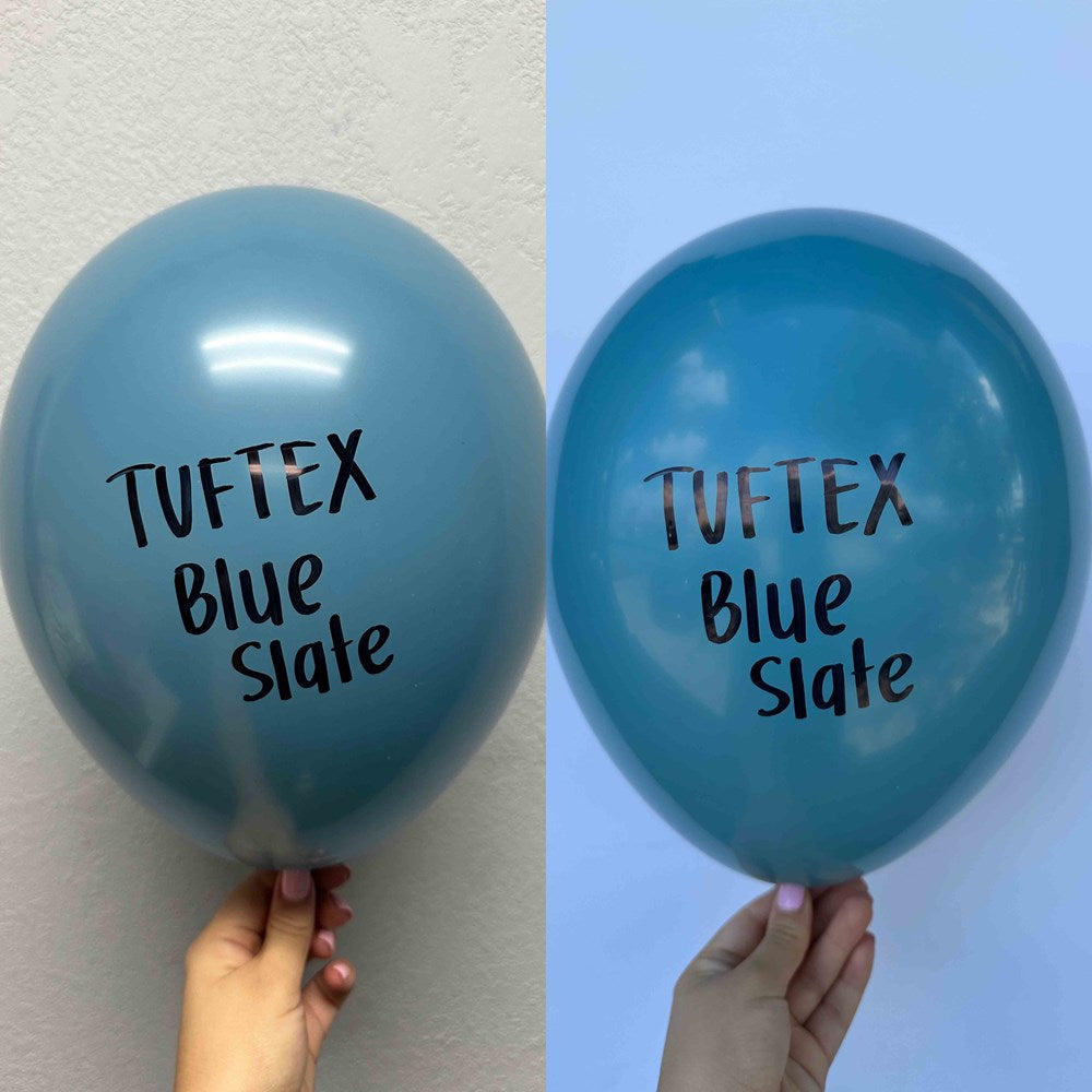 Two blue latex balloons labeled Tuftex Blue Slate, one round and inflated, one slightly deflated, held against plain.