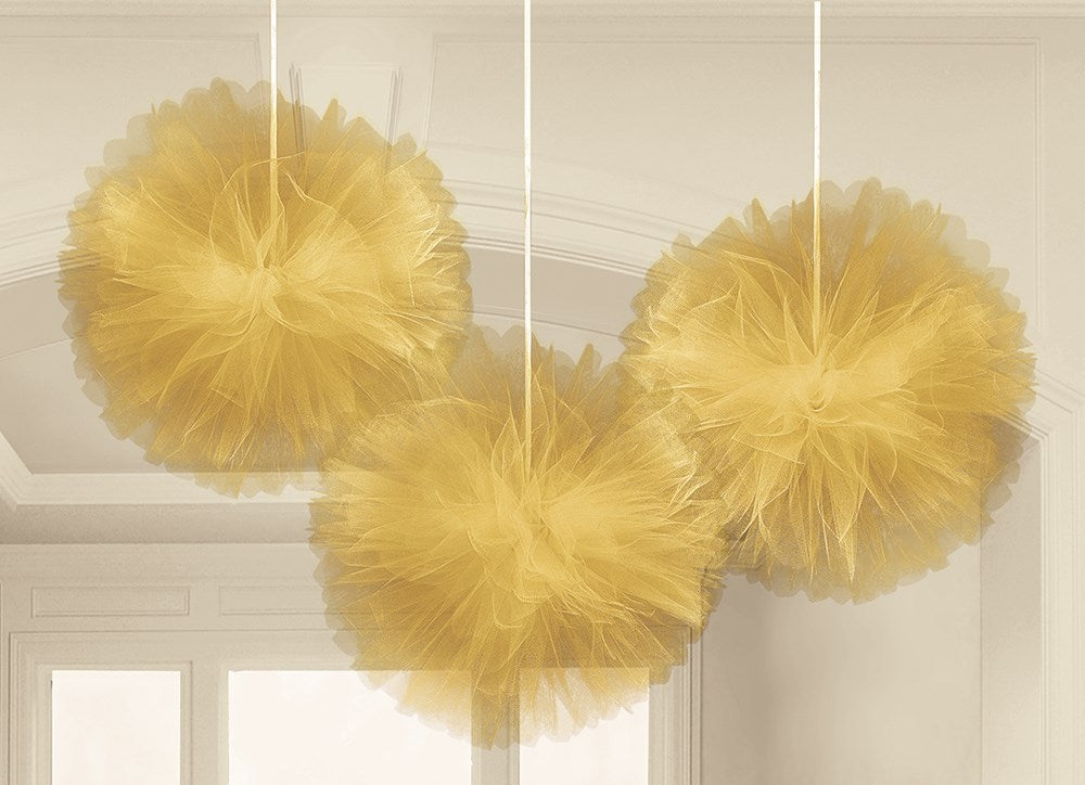 Three gold tulle fluffy pom-pom decorations hanging from white ribbons.