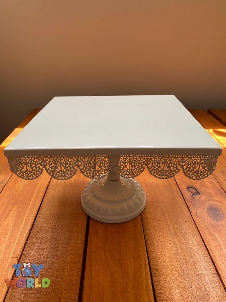 White metal square cake stand with scalloped lace-edge detail and pedestal base.