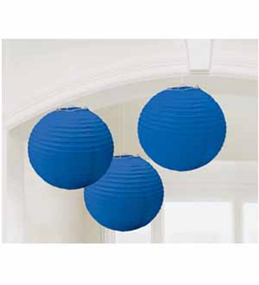 Three bright royal blue round paper lanterns hanging indoors with a white arch background.