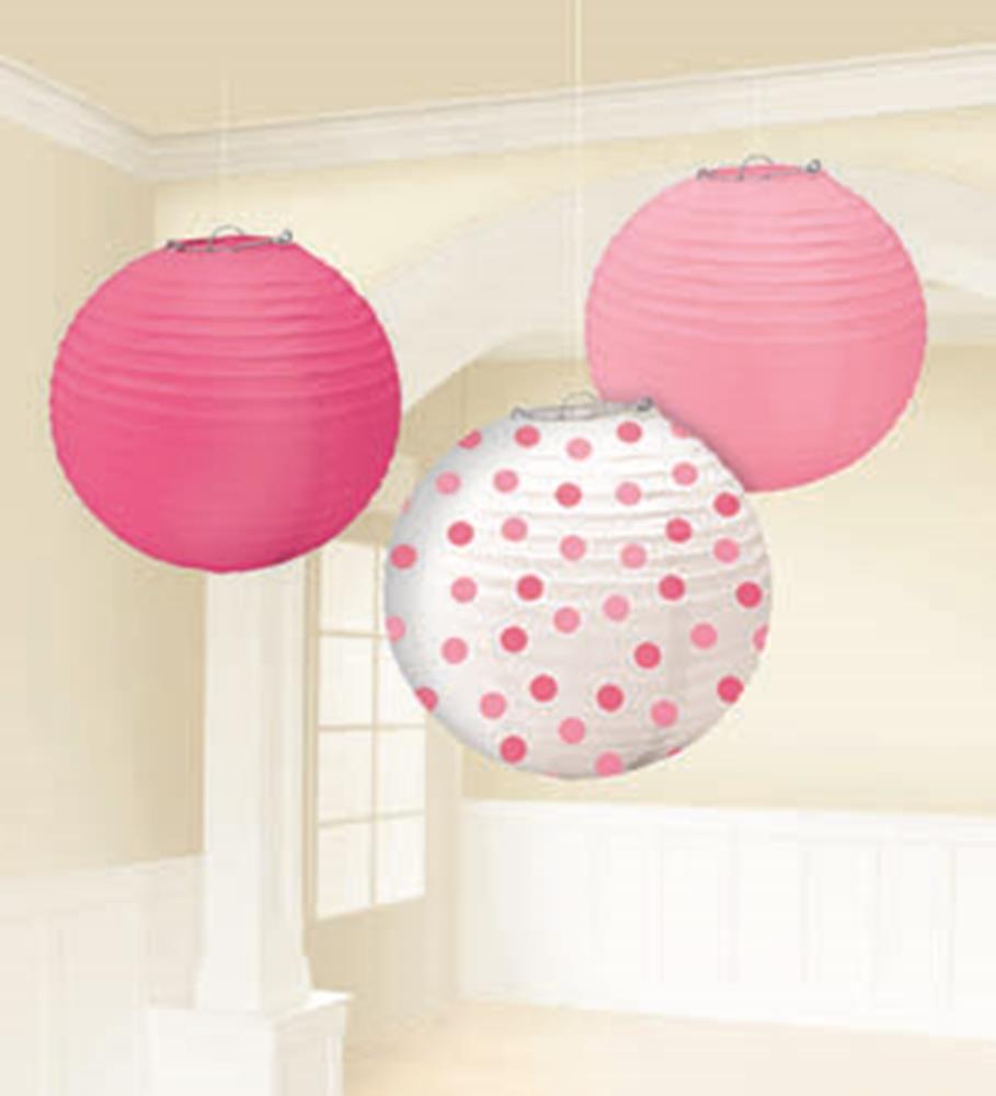 Three round paper lanterns in shades of pink, one solid light pink, one solid dark pink, and one white with pink polka dots,