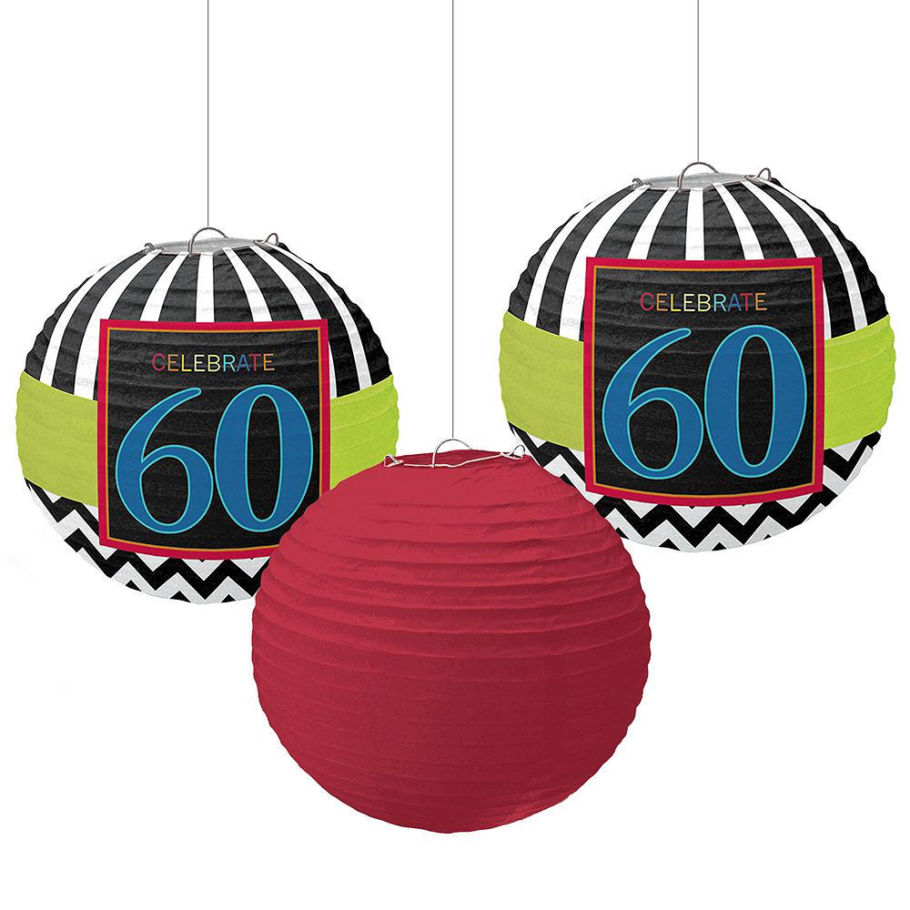 Three hanging paper lanterns including two black and white striped with "Celebrate 60" blue and red design, and one solid.