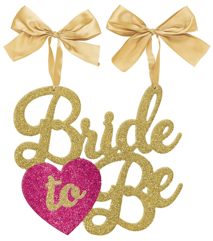 Gold glitter script "Bride to Be" sign with a pink glitter heart and two gold satin bow ties attached.