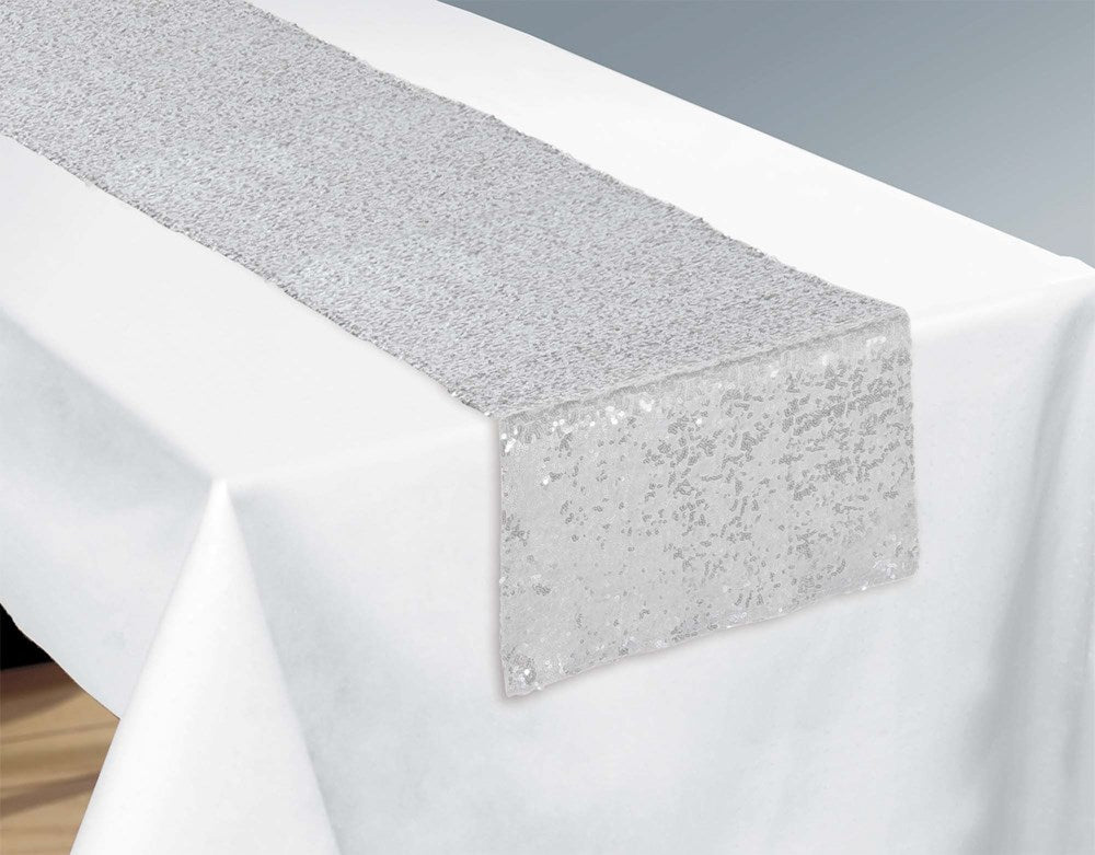 Silver sequin table runner with a sparkling texture, measuring 13 by 72 inches, laid on a white tablecloth.