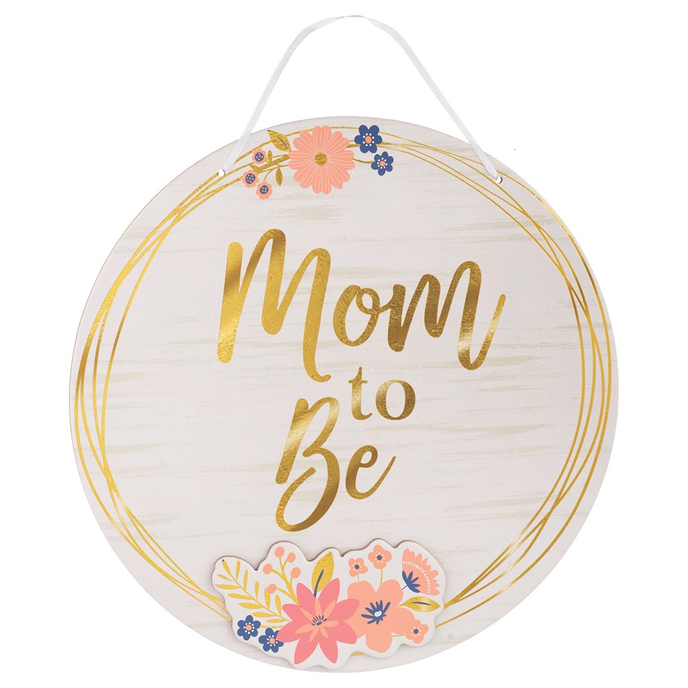 Round white wood sign with gold script "Mom to Be" and pink and blue floral accents, hanging rope.