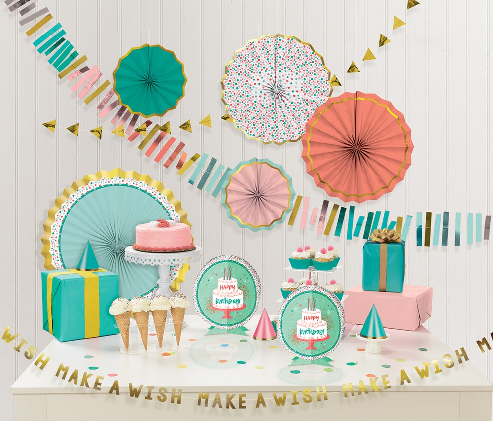 Colorful birthday room decorating kit with round paper fans, pastel gift boxes, cupcake stands, and "Make a Wish" gold.