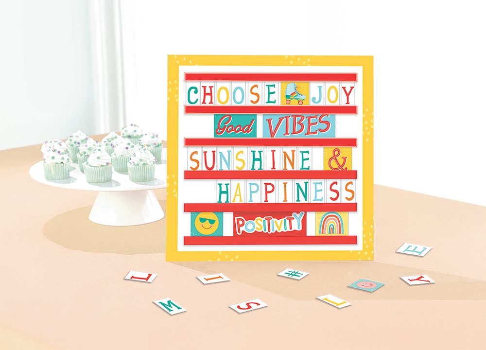 Yellow-framed message board with multicolored letter tiles displaying a positive quote and scattered tiles on a beige.