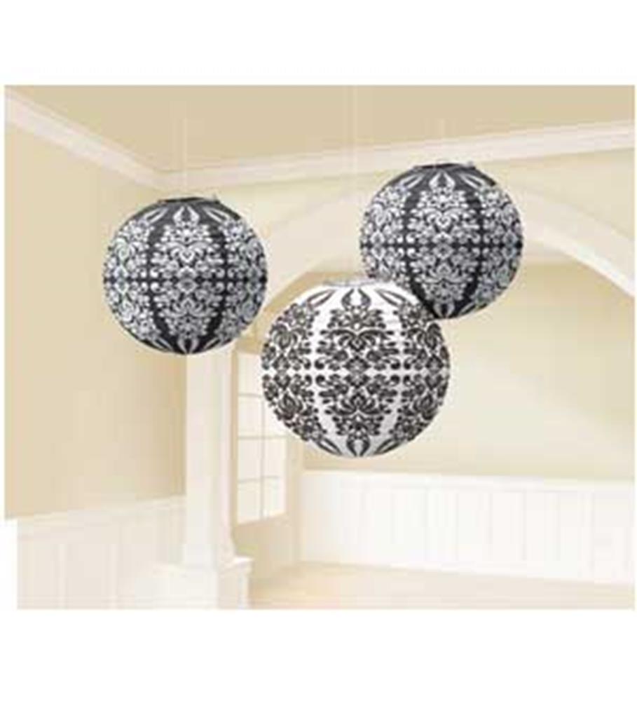 Three black and white paper lanterns with intricate damask patterns hanging indoors.