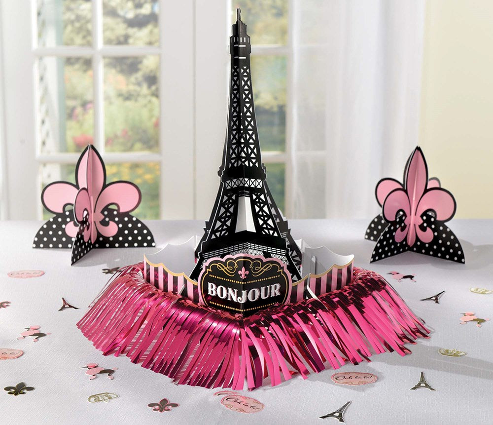 Black Eiffel Tower centerpiece with pink foil fringe and pink fleur-de-lis accents on white tablecloth.