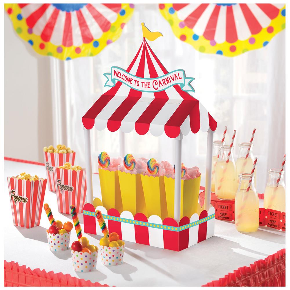 Colorful carnival-themed table centerpiece featuring a popcorn cart with red and white stripes, yellow popcorn, and "Welcome