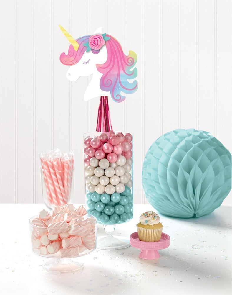 Unicorn head centerpiece with pastel pink, purple, and blue mane on a stick over a clear vase filled with pink, white, and.