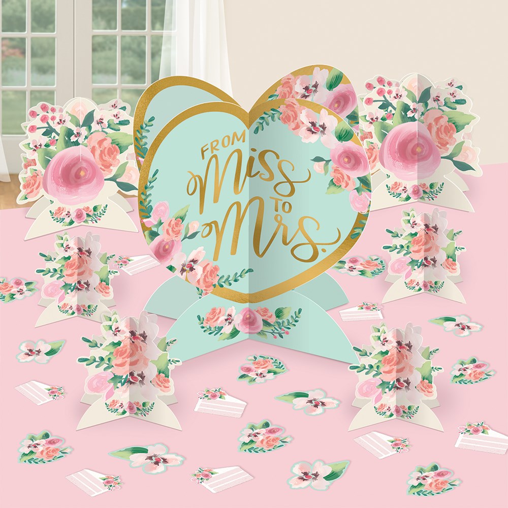 Heart-shaped centerpiece with gold lettering "From Miss to Mrs" surrounded by pink and white floral accents on a pastel.