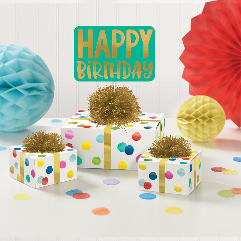 Three white gift boxes with colorful polka dots and gold pom-poms, accompanied by a teal and gold "Happy Birthday" sign and.