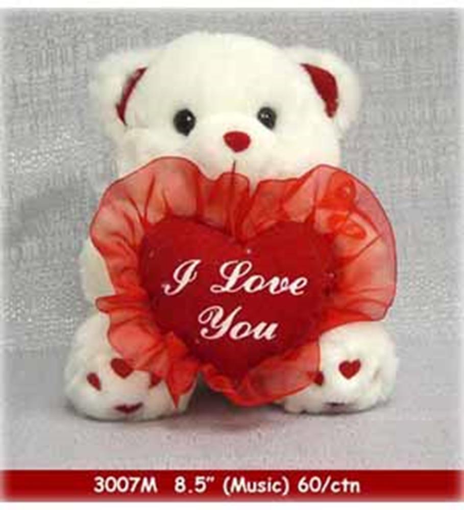 White plush teddy bear holding a red heart-shaped pillow with "I Love You" embroidered in white.
