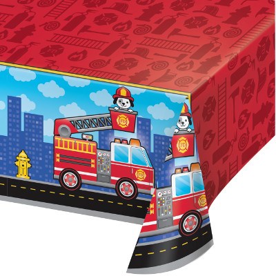 Red plastic tablecover with all-over print of cartoon fire trucks, firefighters, and cityscape, measuring 54 by 102 inches.