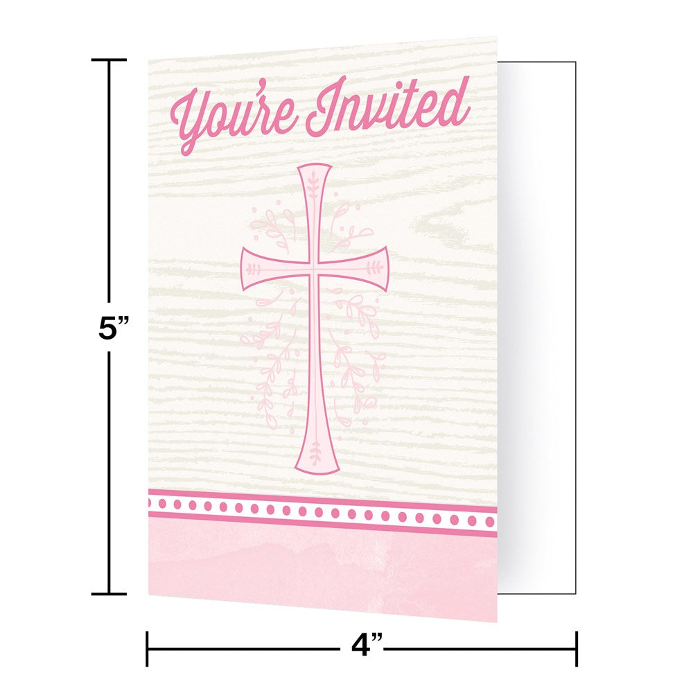 Pink folded invitation card with a cross and decorative dot border on a light wood grain background, 5x4 inches.