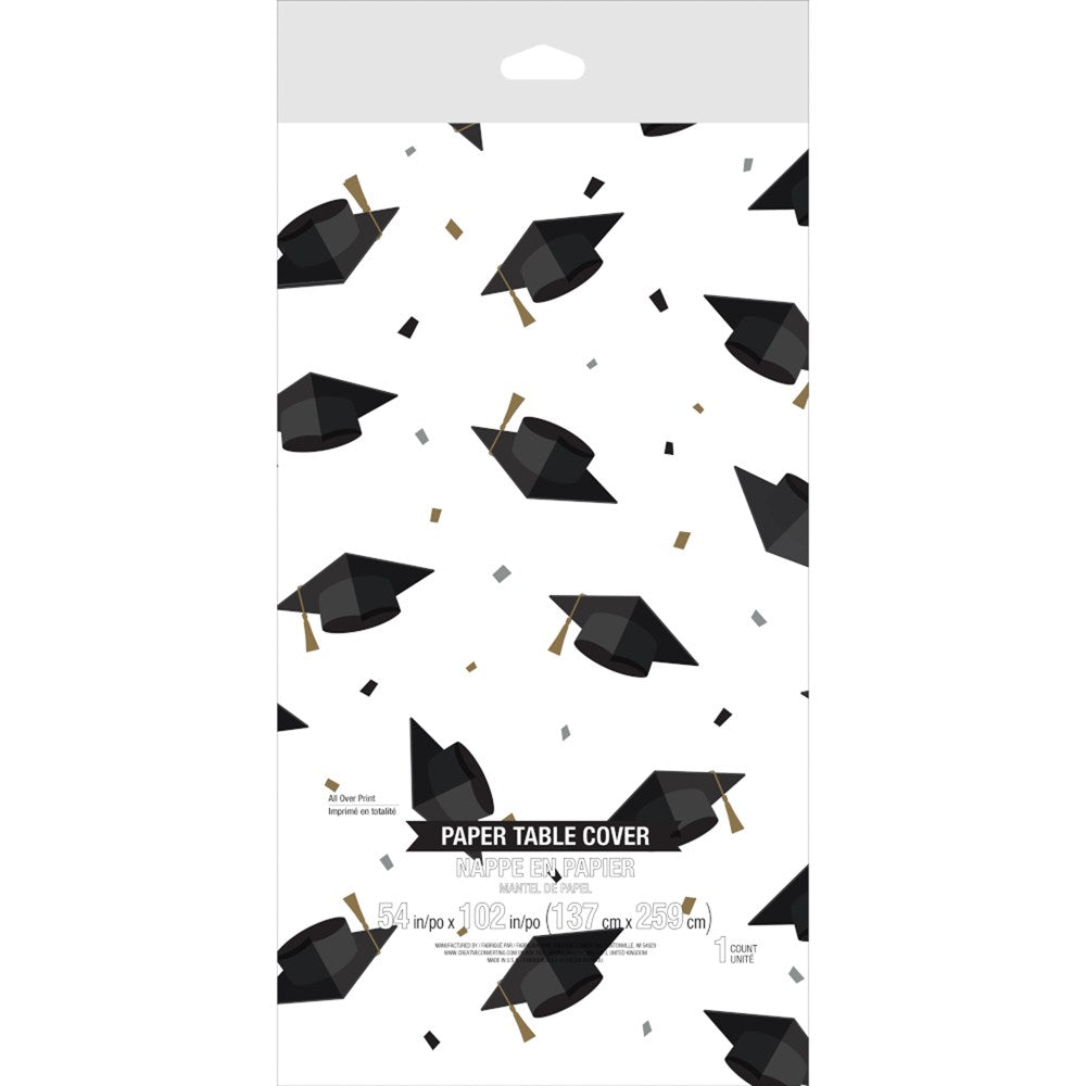 White paper table cover with scattered black graduation caps and gold confetti accents.