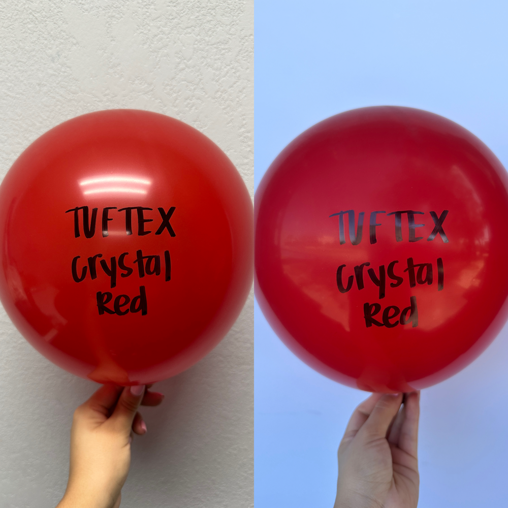 Large shiny red latex balloon with black "Tuftex Crystal Red" text, held by hand.