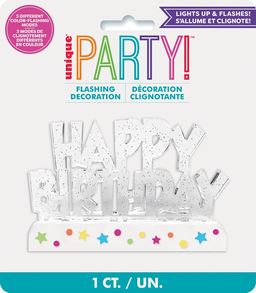 White glittery 'Happy Birthday' cake decoration with multicolored stars on a rectangular base.