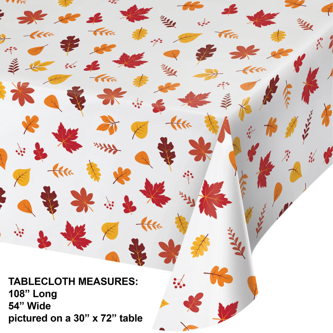 White plastic tablecover with scattered orange, red, brown, and yellow autumn leaves pattern.