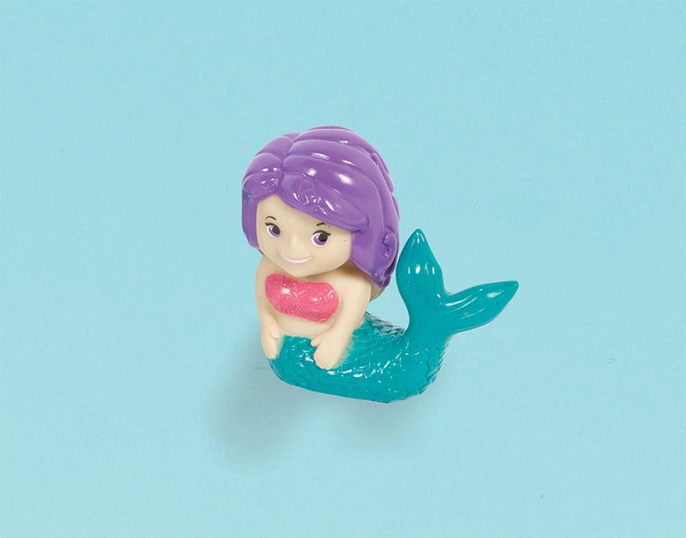 Small plastic mermaid squirt toy with purple hair, pink top, and teal tail on blue background.