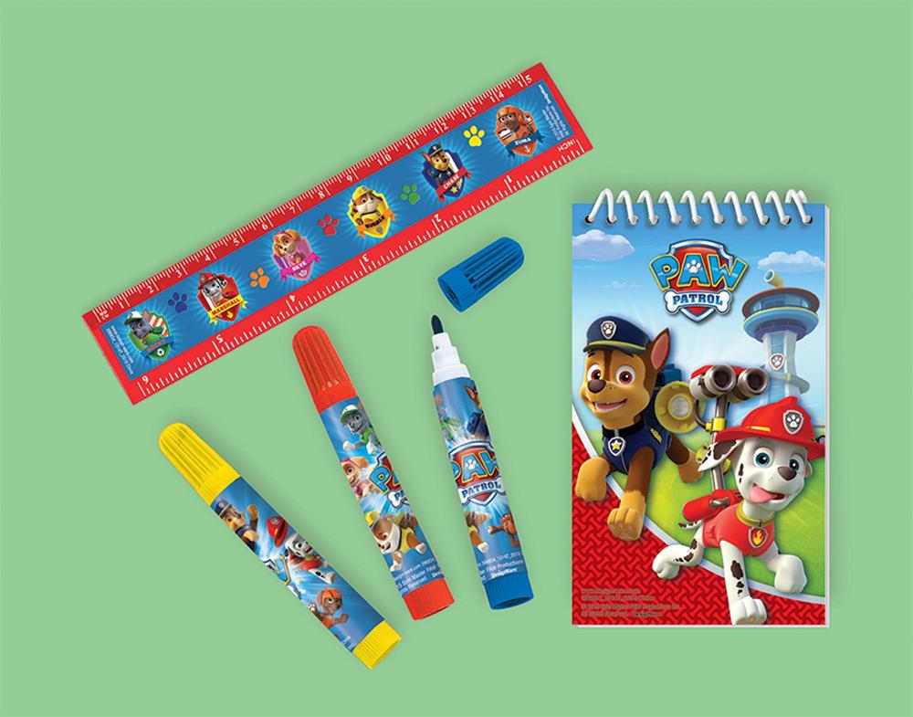 Paw Patrol themed stationery set with spiral notebook, red ruler, yellow and red markers, and white glue stick on green.