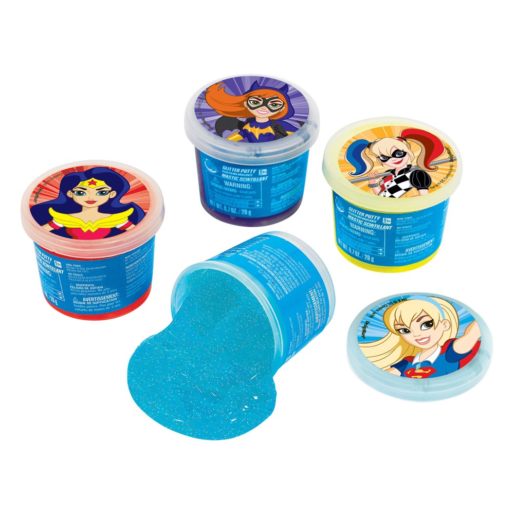 Set of six DC Super Girl-themed ooze putty containers with colorful character lids and bright blue slime spilling from one.