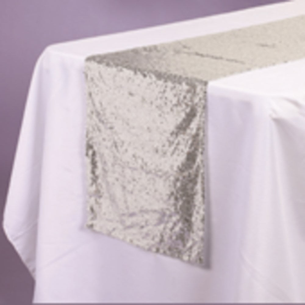 Silver sequin fabric table runner measuring 14 by 108 inches draped over white tablecloth.
