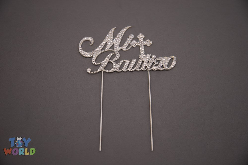 Silver rhinestone cake topper spelling "Mi Bautizo" with a cross above the text, two long prongs for inserting into cake.