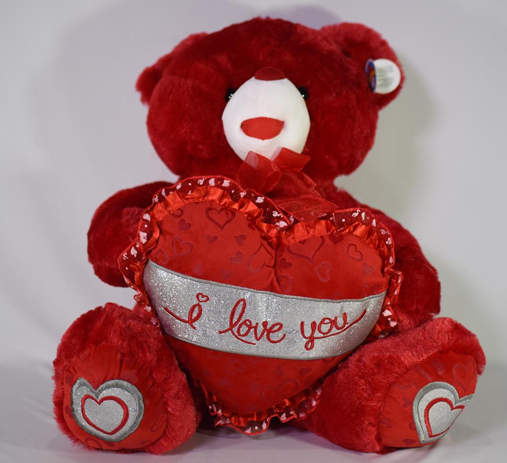 Red plush teddy bear holding a red heart with "I love you" scripted in silver and red hearts embroidered on its feet.