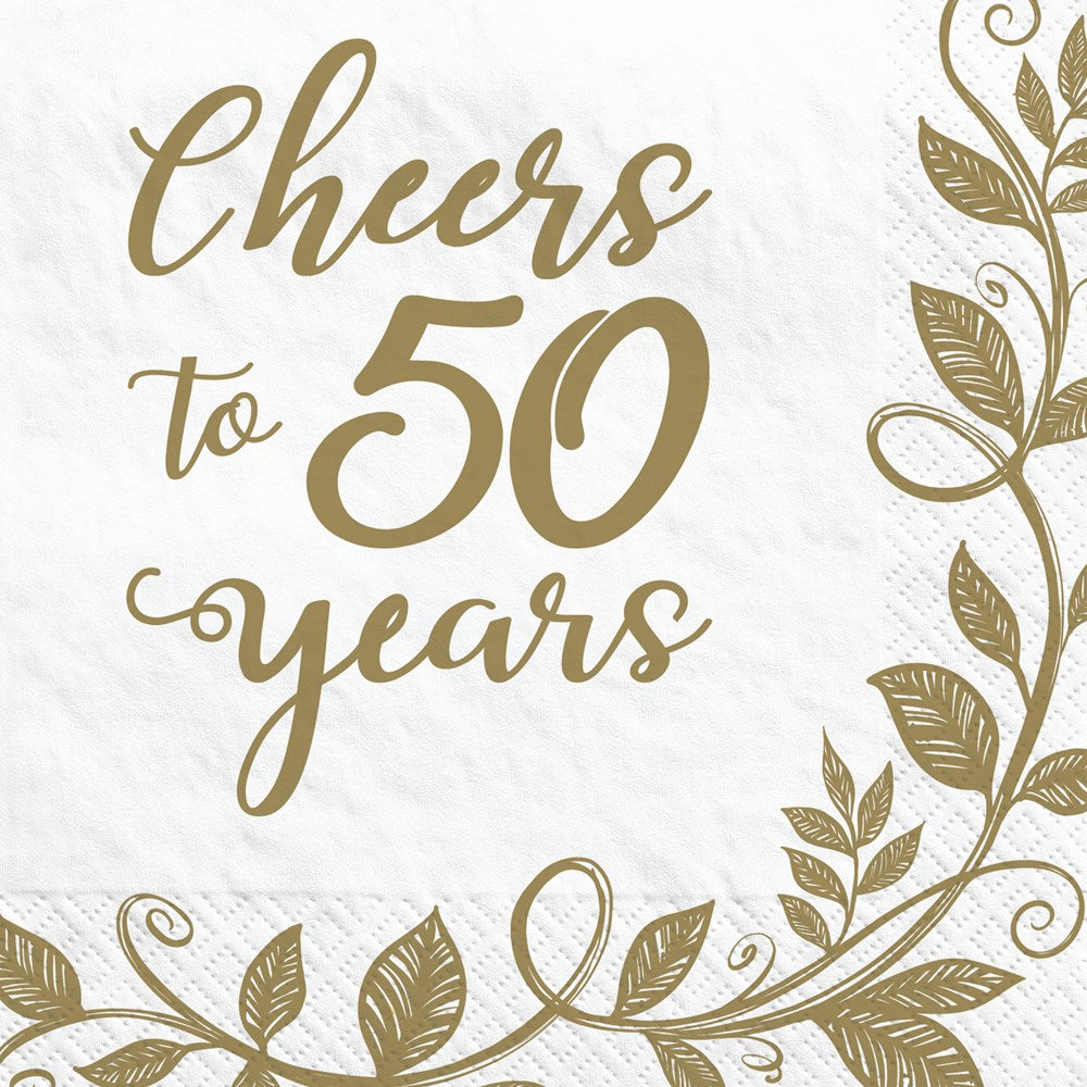 White beverage napkin with gold foil script reading "Cheers to 50 years" and gold leafy vine border.