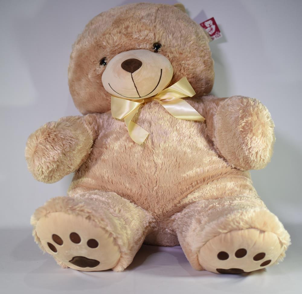 Large beige plush teddy bear with round ears, a smiling embroidered face, and a yellow satin bow around its neck.