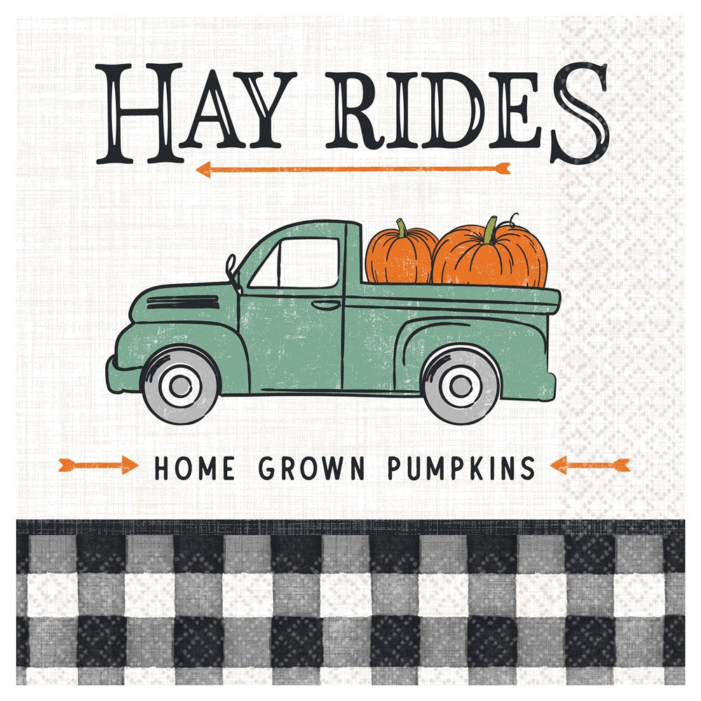 White luncheon napkin with green vintage truck carrying orange pumpkins, "Hay Rides" text, and black buffalo check border.