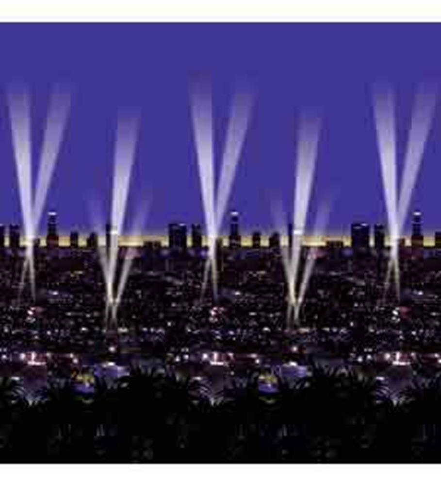 Purple night sky with black city skyline silhouette and white spotlight beams.