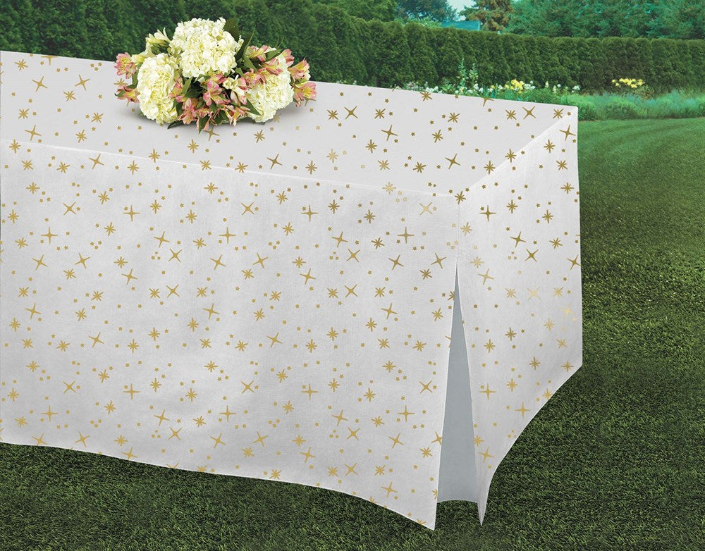 White rectangular table cover with shimmering gold star confetti pattern, draped over table outdoors.