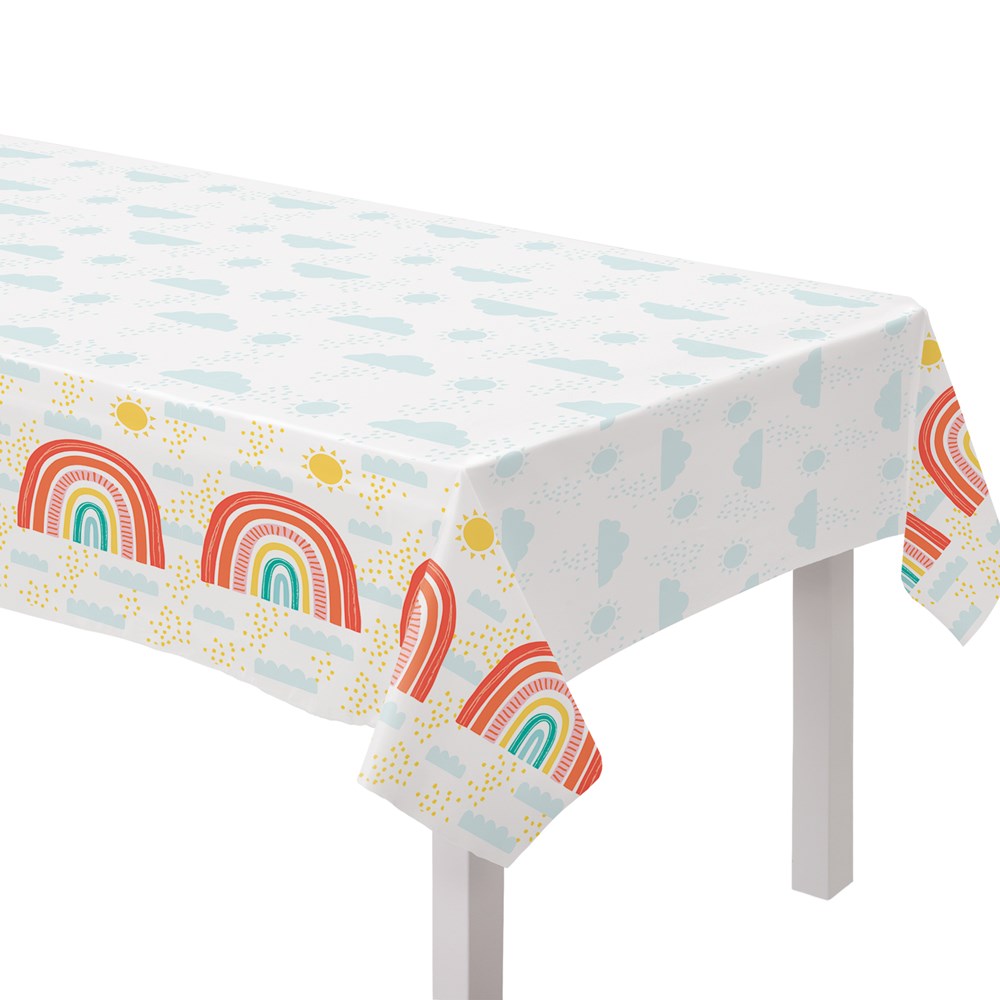 White plastic table cover with pastel blue clouds and colorful retro rainbows along the edges.