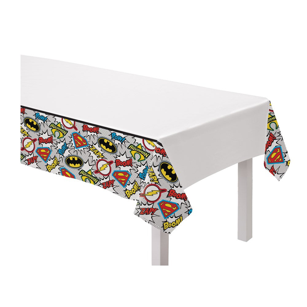 White plastic table cover with colorful Justice League logos and superhero emblems along the edges.