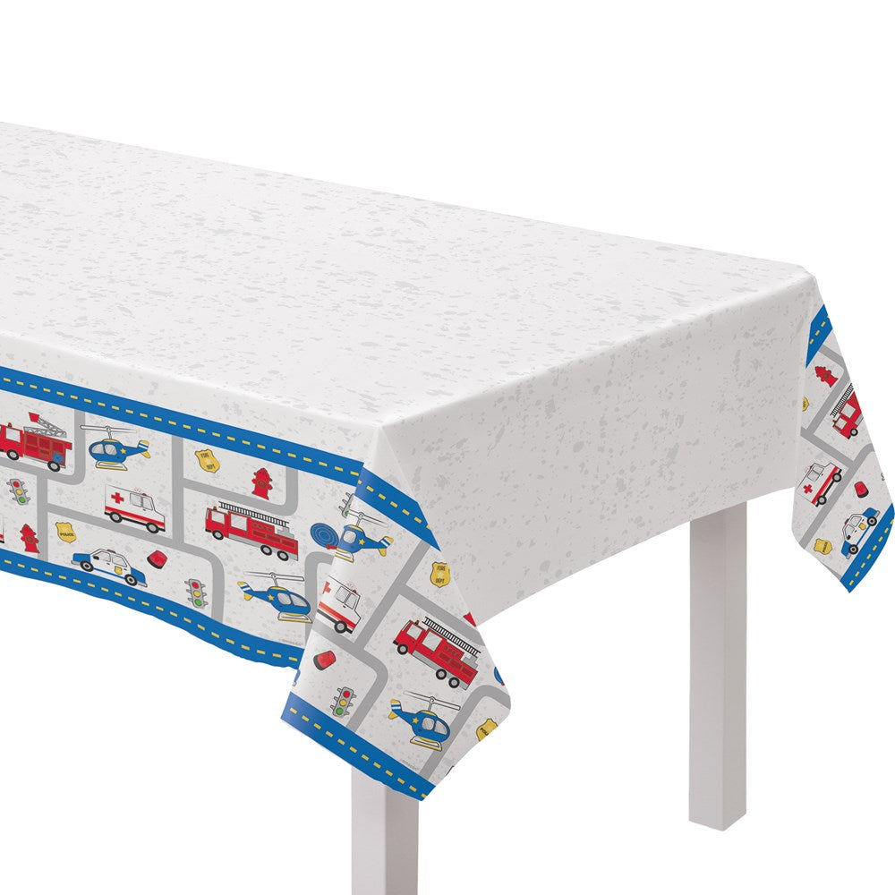 White plastic rectangular table cover with blue border featuring red fire trucks, police cars, and emergency symbols.