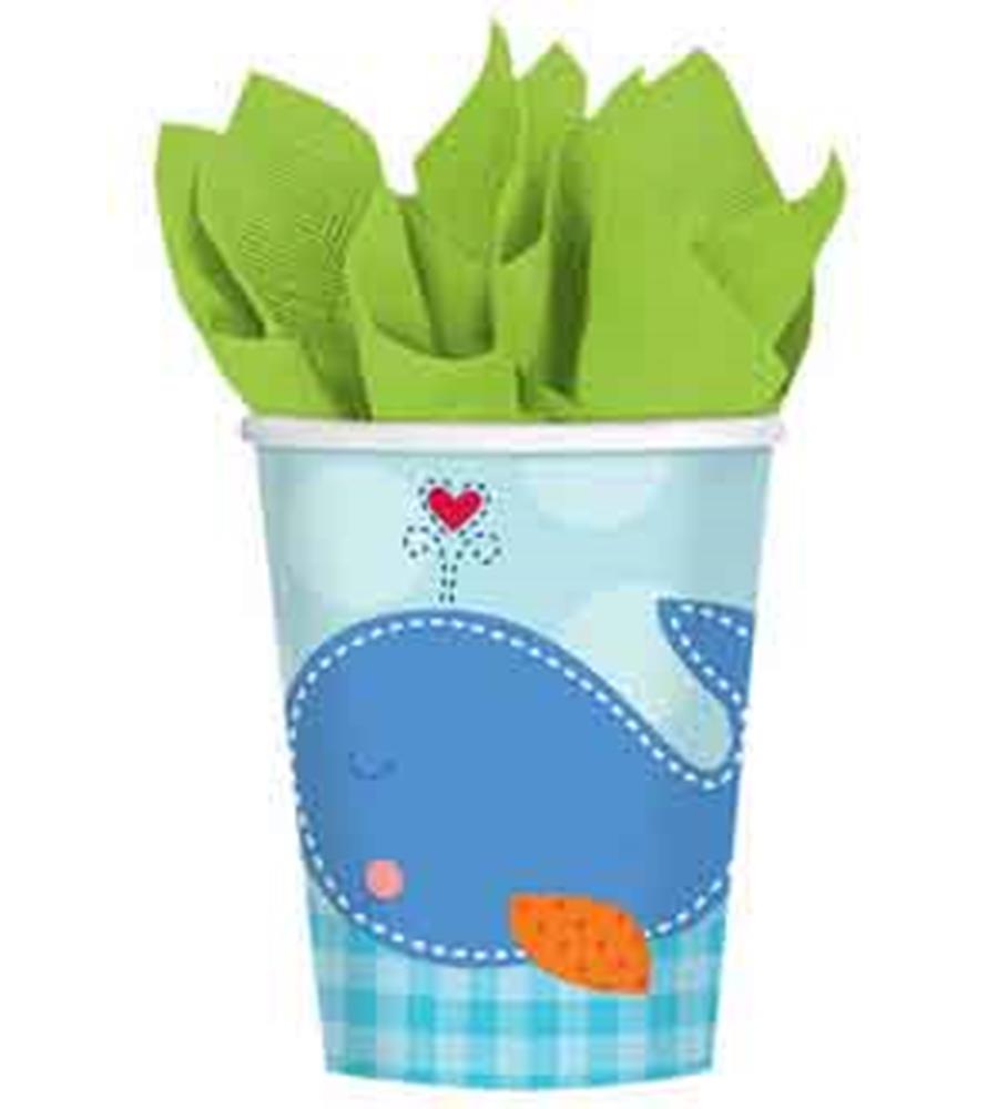 Light blue paper cup with smiling blue whale and orange fin, accented by red heart water spout and green napkins inside.