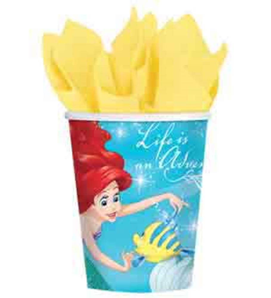 Blue Disney cup featuring Ariel with red hair reaching toward a yellow fish, filled with yellow napkins.